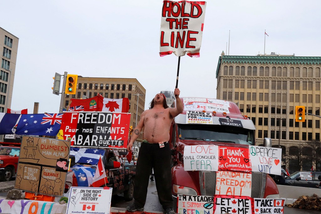 A person holds a sign in front of trucks blocking a downtown street as truckers and their supporters continue to protest against the coronavirus disease (COVID-19) vaccine mandates in Ottawa, Ontario, Canada.