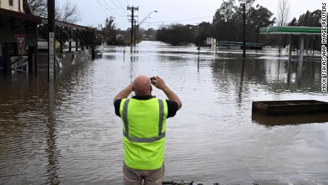 A local citizen takes a photo of a flooded road in Camden in southwest Sydney, Sunday, July 3, 2022.