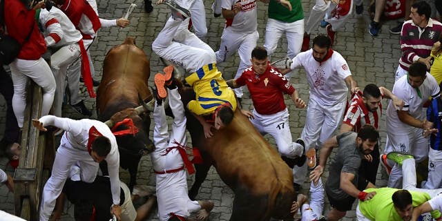 Runners fall and are beaten by bullfights during the bull run at the San Fermin Festival in Pamplona, ​​Spain, on Monday, July 11, 2022.