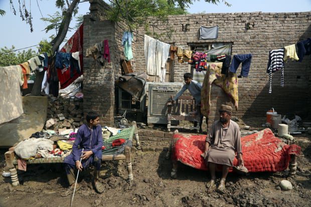 A family rests after salvaging their belongings from their flood-stricken home, in Charsadda, Pakistan.