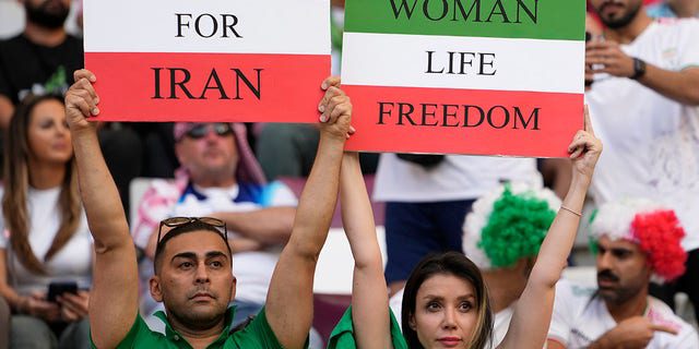 Iranian football fans hold banners that read 